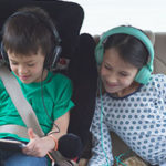 Image of two children playing with a tablet in a car