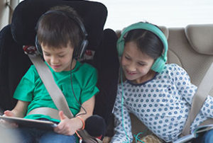 Image of two children playing with a tablet in a car