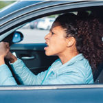Image of woman banging fist on steering wheel in anger