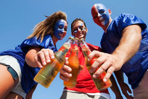 Image of football fans clinking bottles of beer