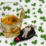 Image of car keys next to a glass of whiskey on a background of shamrocks