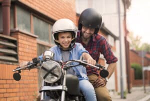 Image of a child sitting on a motorcycle with their parent