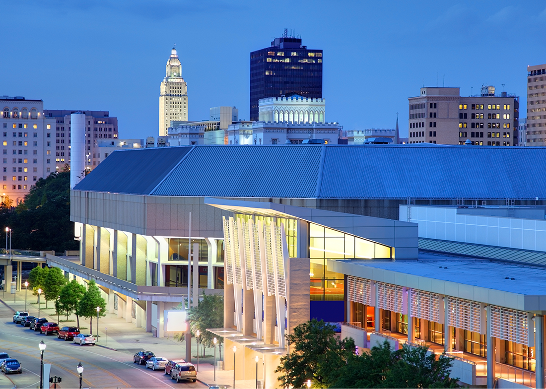 Modern architecture and skyline of a city at dusk, featuring illuminated buildings and urban scenery.