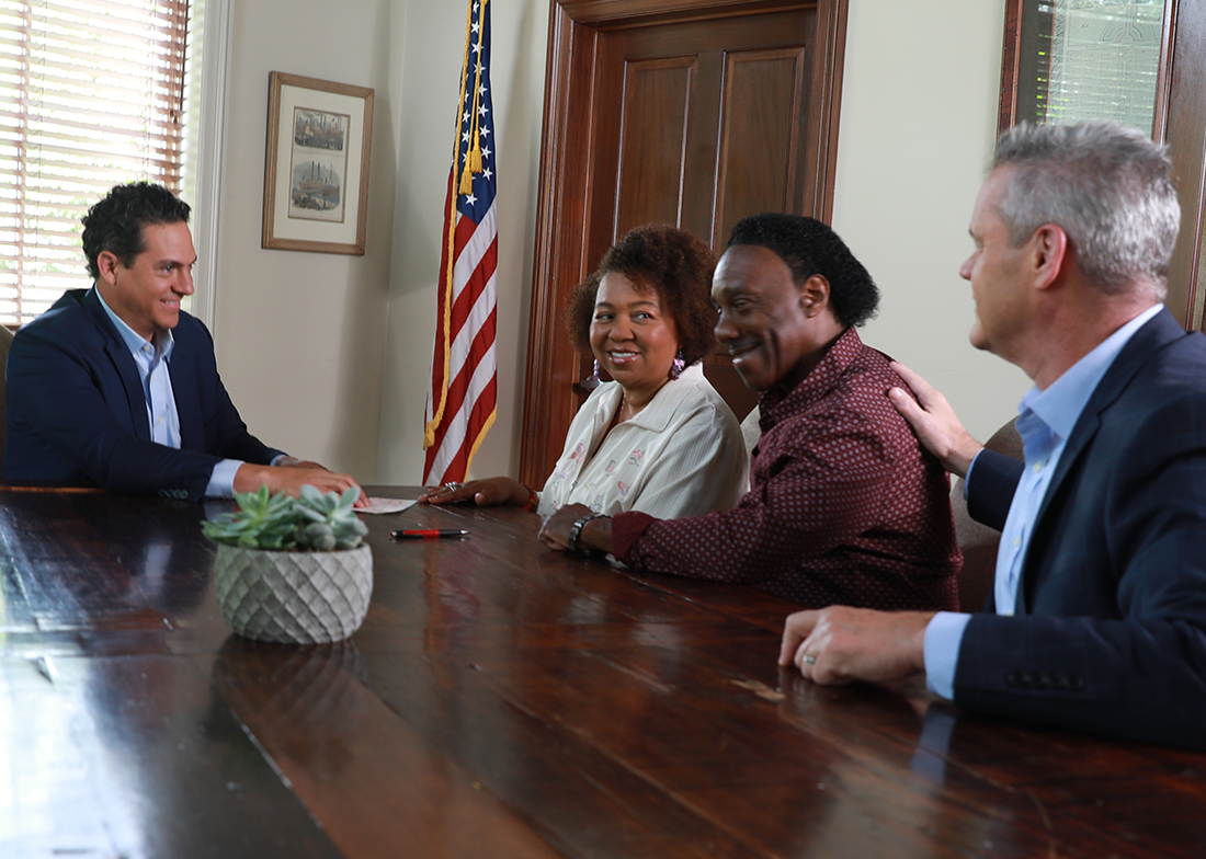Team having a positive meeting around a table with an American flag in the background.