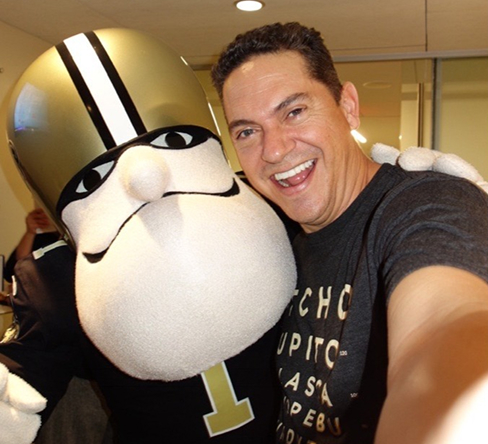 Chad Dudley with mascot Man taking a selfie with a cheerful sports mascot, both smiling and enjoying a fun moment together.